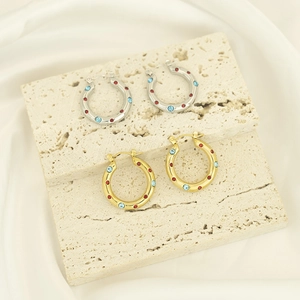 Detail of silver and gold hoop earrings with colorful zircon stones on stone bases