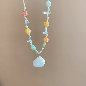 Detail of colorful beads and a natural white shell pendant on a summer beach necklace