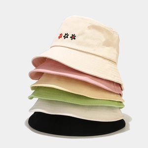 Detail of stacked cotton bucket hats featuring delicate small flower embroidery design