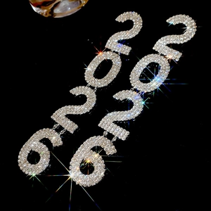 Macro shot of sparkling silver 2020 number earrings with rhinestones on black background