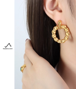 Detail of twisted gold stainless steel hoop earring worn by a model for a modern look