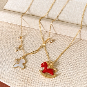 Detail of gold horse pendant necklace with white mother-of-pearl and red enamel charms