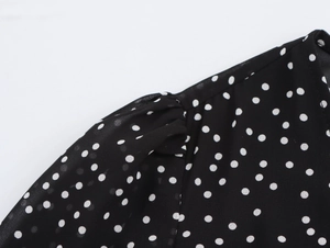 Detailed macro view of black polka dot chiffon fabric with elegant shoulder pleats