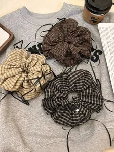 Close-up of three plaid scrunchies with black ribbons on a cozy autumn grey sweater background