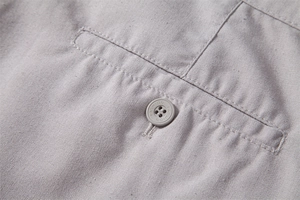 Detailed macro view of light grey cotton linen fabric texture and fashion button detail