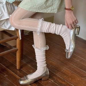 Detail showing white ruffled lace stockings and ribbed slouch socks on a person