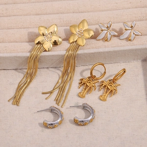 Lot de boucles d'oreilles fleurs dorées et argentées et puces palmier sur plateau