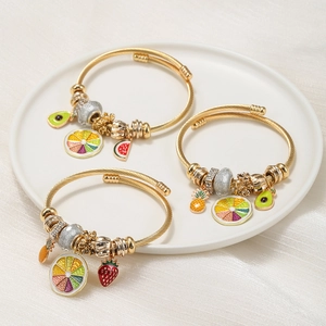 Adjustable gold stainless steel bracelets with colorful enamel fruit charms on white ceramic