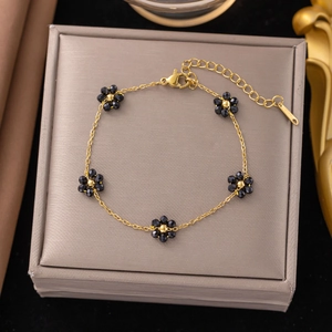Detail of elegant gold chain bracelet with five black floral beads on a jewelry box