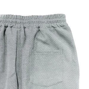 Close-up of gray textured fabric pants showing elastic waistband and back pocket detail