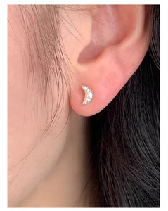 Close-up of a 925 sterling silver croissant earring worn on a person's ear lobe