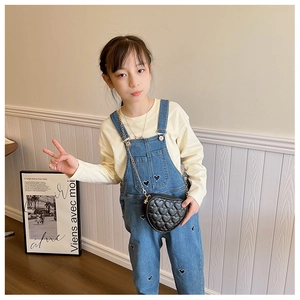 Close-up of heart-shaped black quilted crossbody bag with gold chain strap for kids