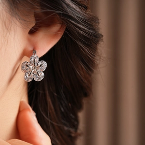 Gros plan d'une boucle d'oreille fleur en argent avec zircons sur une oreille