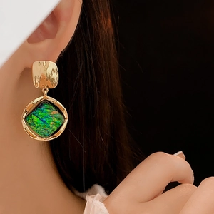 Close-up of vintage resin earrings in green and gold on model showing elegant fit