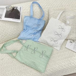Detailed view of canvas tote bags with sequins and metallic bow accents in three colors