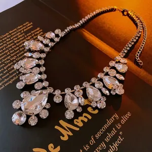 Statement silver necklace with drop-shaped crystals on a vintage book backdrop