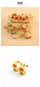 Macro detail of 18K gold-plated irregular earrings with colorful beaded flower textures