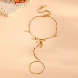 Detail of 18k gold plated finger bracelet featuring dainty beads on a warm stone tray