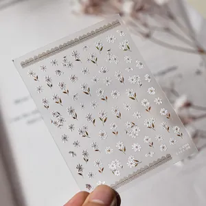 Detail view of 3D embossed floral nail stickers featuring white camellias and daisies