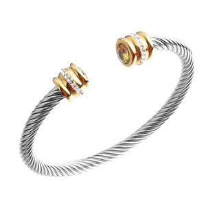 Silver twisted cable cuff bracelet with gold accents and amber stone on white background