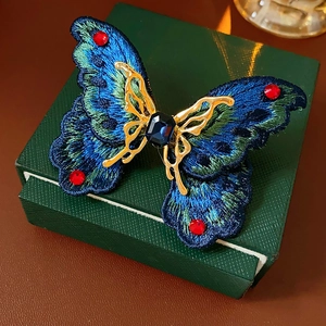 Close-up of vintage butterfly ring featuring blue embroidery and emerald-cut blue stone