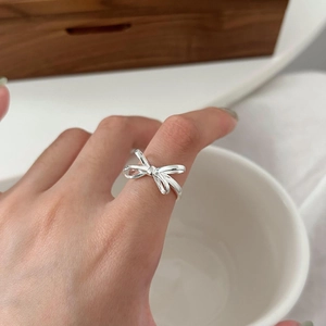 Close-up of elegant silver 925 bow-shaped open ring worn on finger with minimalist decor