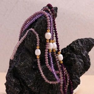 Close-up of purple crystal beads and freshwater pearls on a luxury black stone display