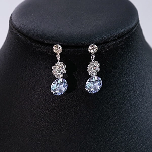 Detailed close-up of sparkling zircon flower earrings on a black display stand