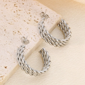 Macro shot of silver twisted rope C-shaped stainless steel earrings on marble