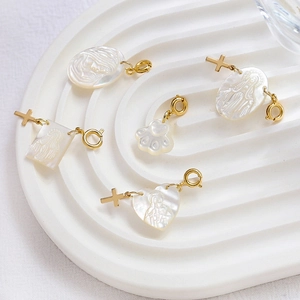 Macro detail of mother-of-pearl heart and cat paw charms with gold-plated lobster clasps