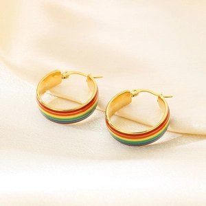 Details von goldenen Creolen mit Regenbogenstreifen auf gelbem Seidenhintergrund