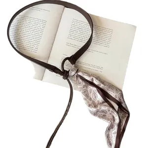 Retro brown leather belt with paisley print silk scarf accessory on vintage books