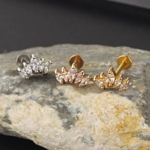 Three marquise zircon labret studs in silver, gold, and rose gold on a stone base
