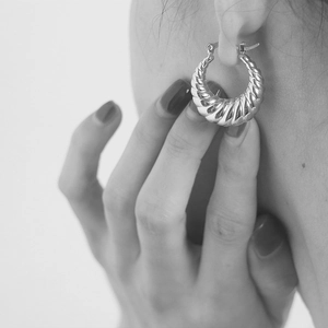 Close-up of elegant silver textured hoop earrings with a stylish twisted thread design