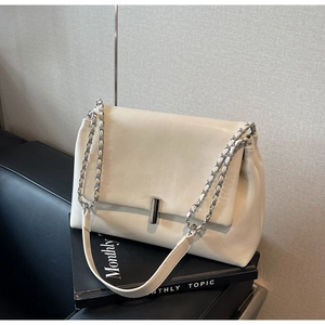 Detail of off-white faux leather handbag featuring silver cylinder lock and chain strap