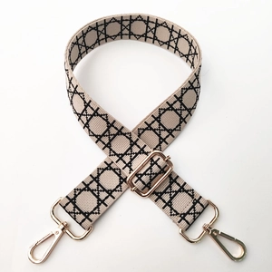 Adjustable beige shoulder strap with black geometric pattern and gold buckles
