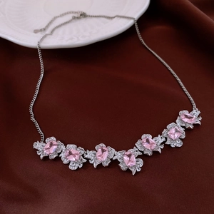 Close-up of pink zircon flower pendant necklace on elegant deep red fabric background