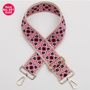 Close-up of pink and black ethnic jacquard bag strap with gold metal hooks and buckle