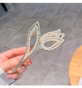 Close-up of golden tulip hair claw clip decorated with small pearls and rhinestones