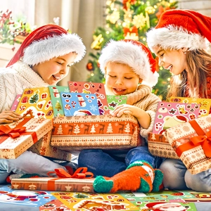 Three happy children opening a Christmas sticker gift box near a festive tree