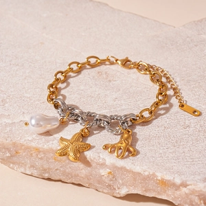 Detail of ocean-themed bracelet featuring golden starfish, octopus charms and pearl pendant