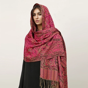 Close-up of pink cashmere-like shawl featuring golden paisley patterns and soft fringe detail