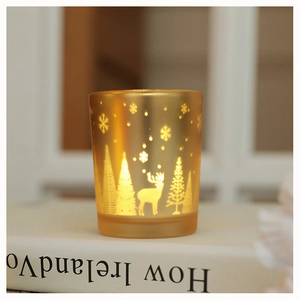 Close-up of golden frosted glass candle holder with elk and snowflake festive patterns