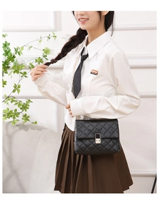 Close-up of black quilted shoulder bag featuring gold chain strap and metal lock detail