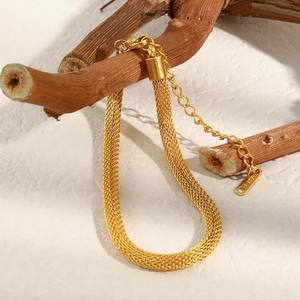 Détail du bracelet maille en acier inoxydable plaqué or 18K sur une branche de bois