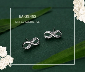 Macro view of silver infinity stud earrings with small diamonds on green backdrop
