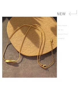 Detail of twisted gold tube pendant on fine snake chain with 18K gold plating