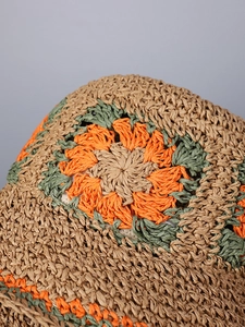 Close-up of handmade straw hat featuring colorful floral crochet and woven textures