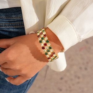 Close-up of a wide gold bangle with multi-colored crystals worn on a female wrist