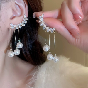 Macro view of gold pearl tassel earrings featuring sparkling crystals and drop chain design